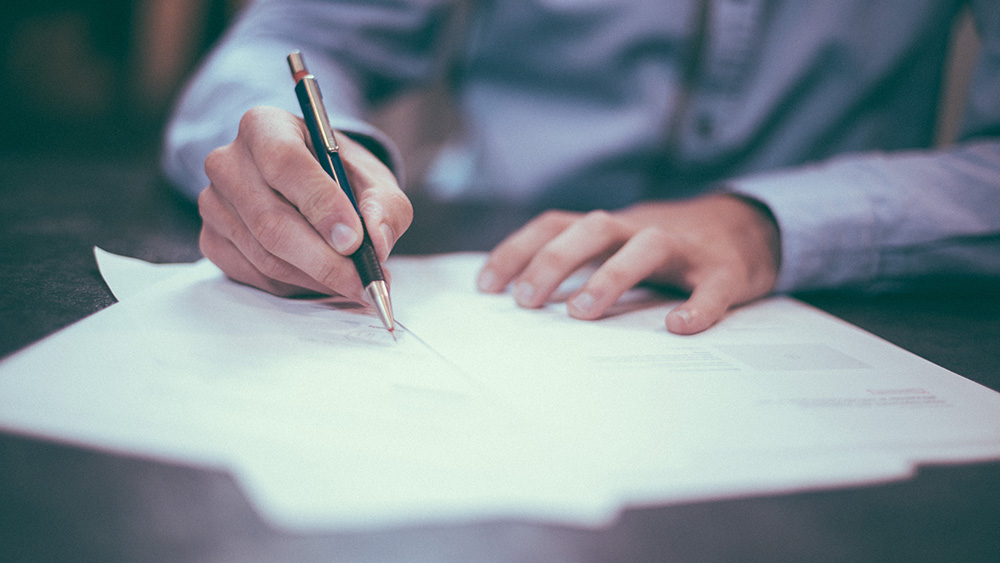 A person writes notes down on a sheet of paper.