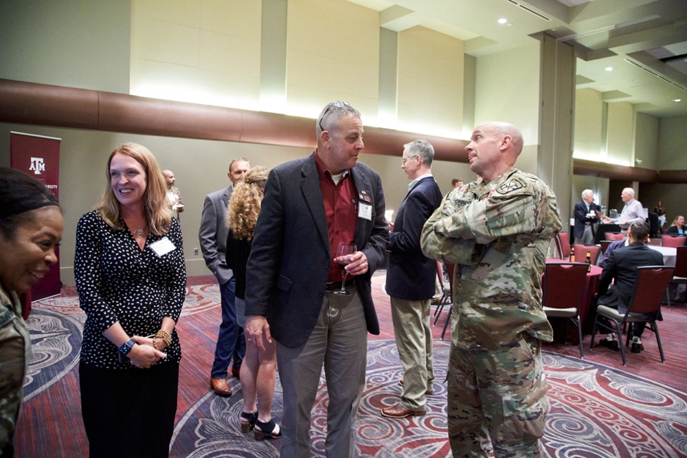 Guests conversing with one another during the military social event with one man dressed in a military uniform